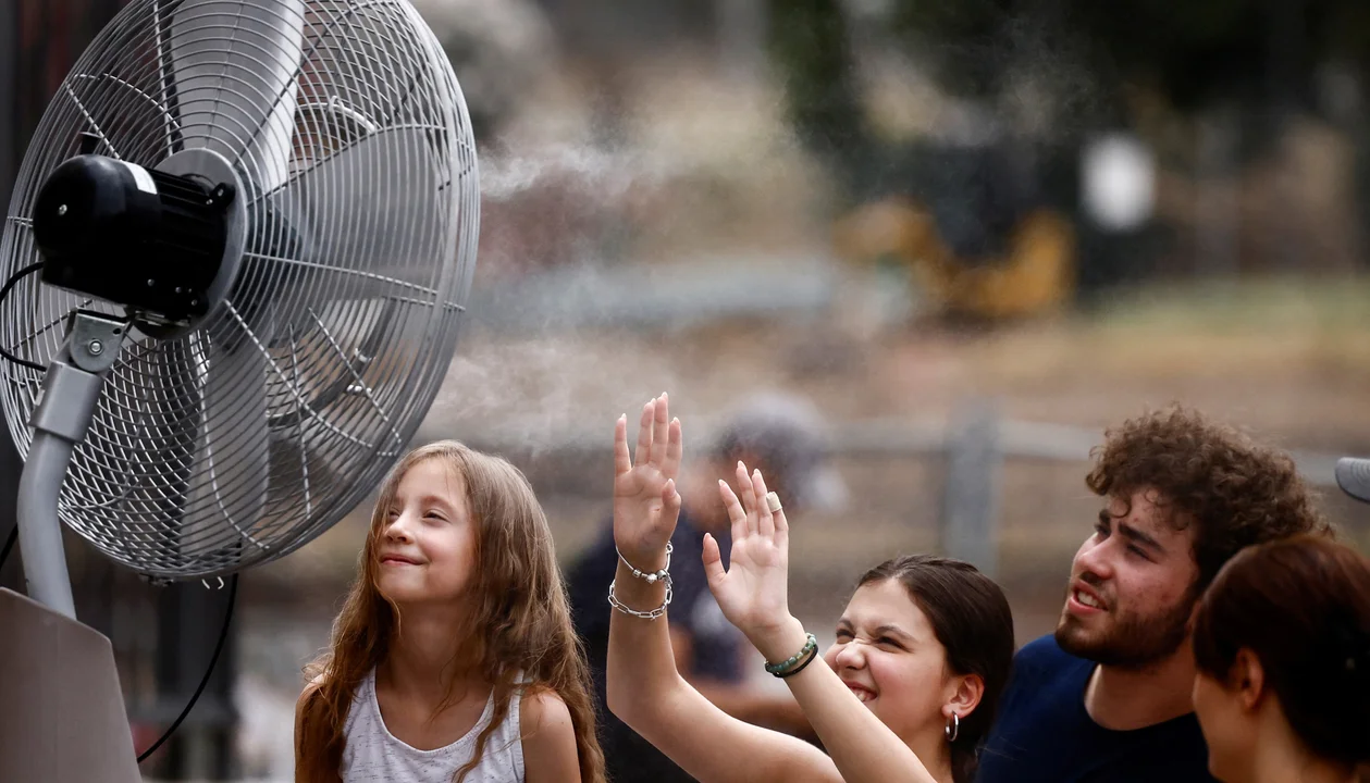 La gente se refresca frente a un ventilador en medio de la ola de calor