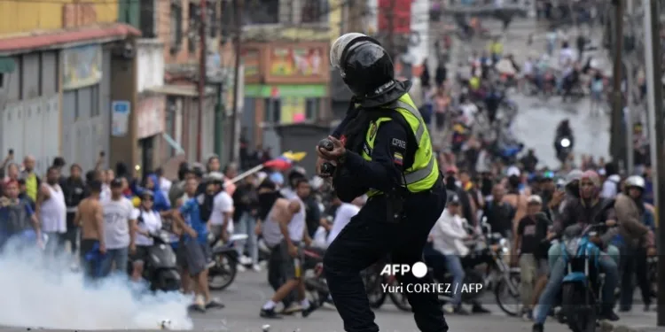 Un policia antidisturbios utiliza gases lacrimogenos contra manifestantes opositores al gobierno de Nicolas Maduro.